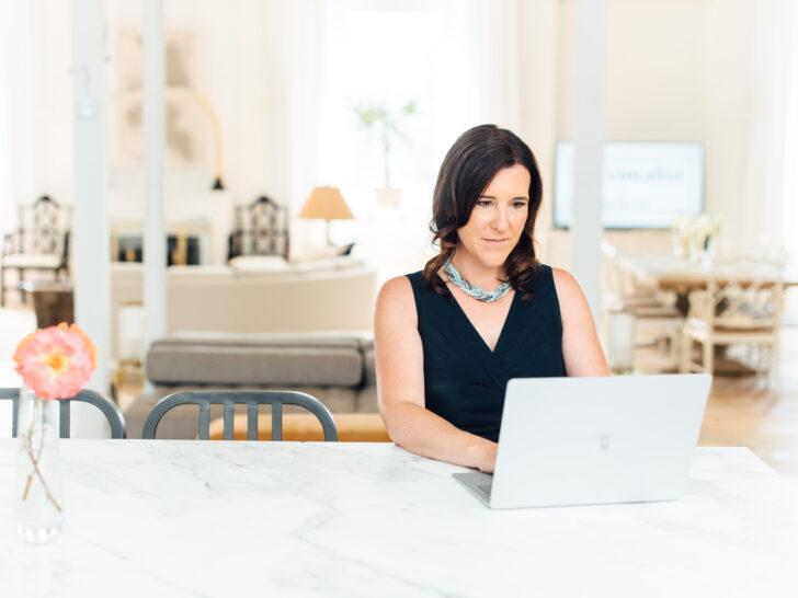 Robyn Marie, certified life coach, working on a laptop in a bright, modern space—offering virtual coaching support for women and teens.